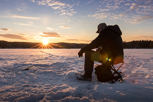 Man ice fishing at dawn