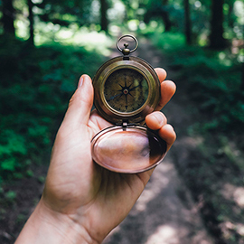 Person holding a compass in the woods